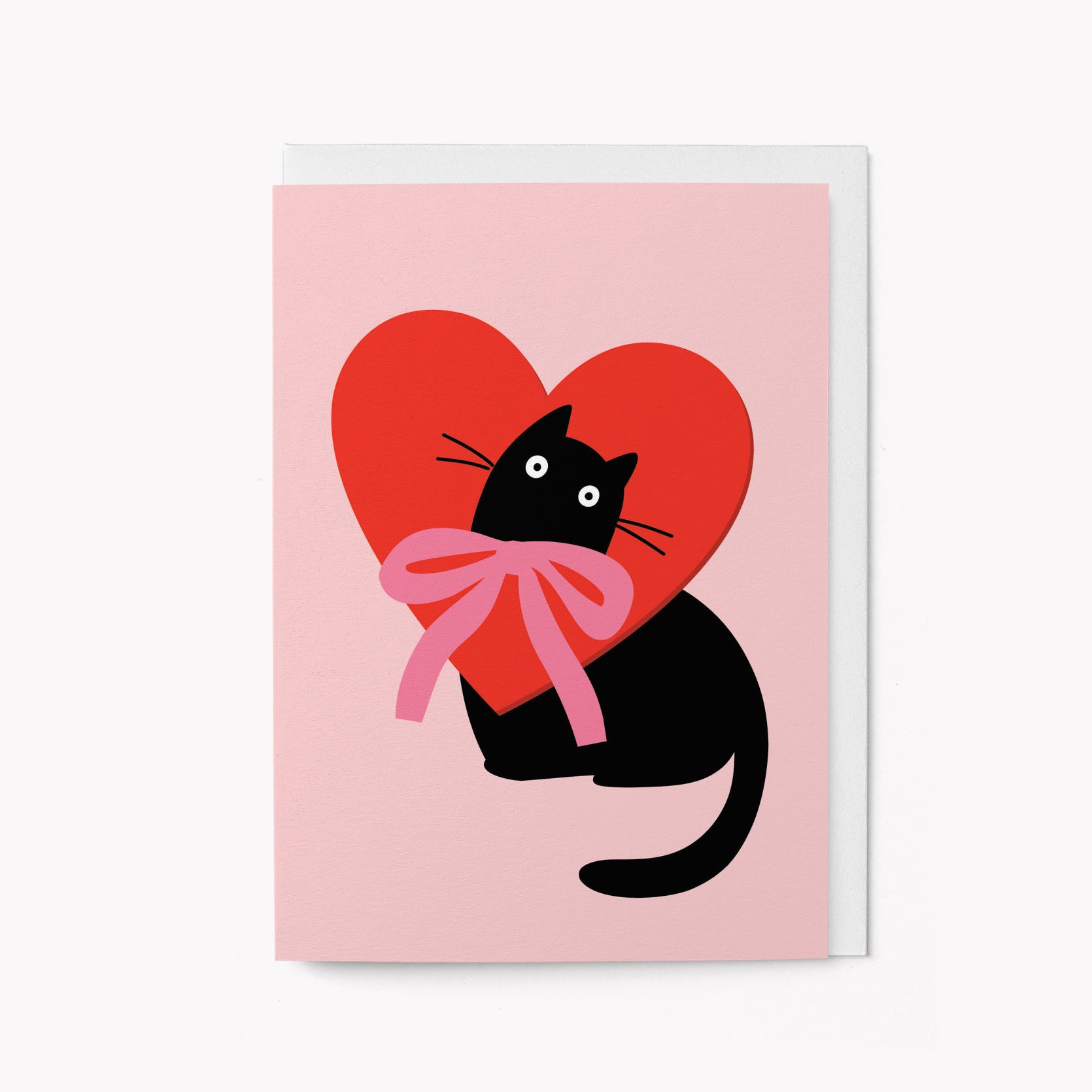 Illustration of a black cat holding a red heart with a pink bow on a pink background greeting card