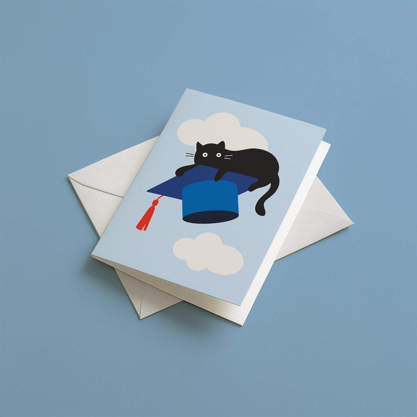 Greeting card with a black cat on a blue graduation cap, featuring a white envelope on a blue background.