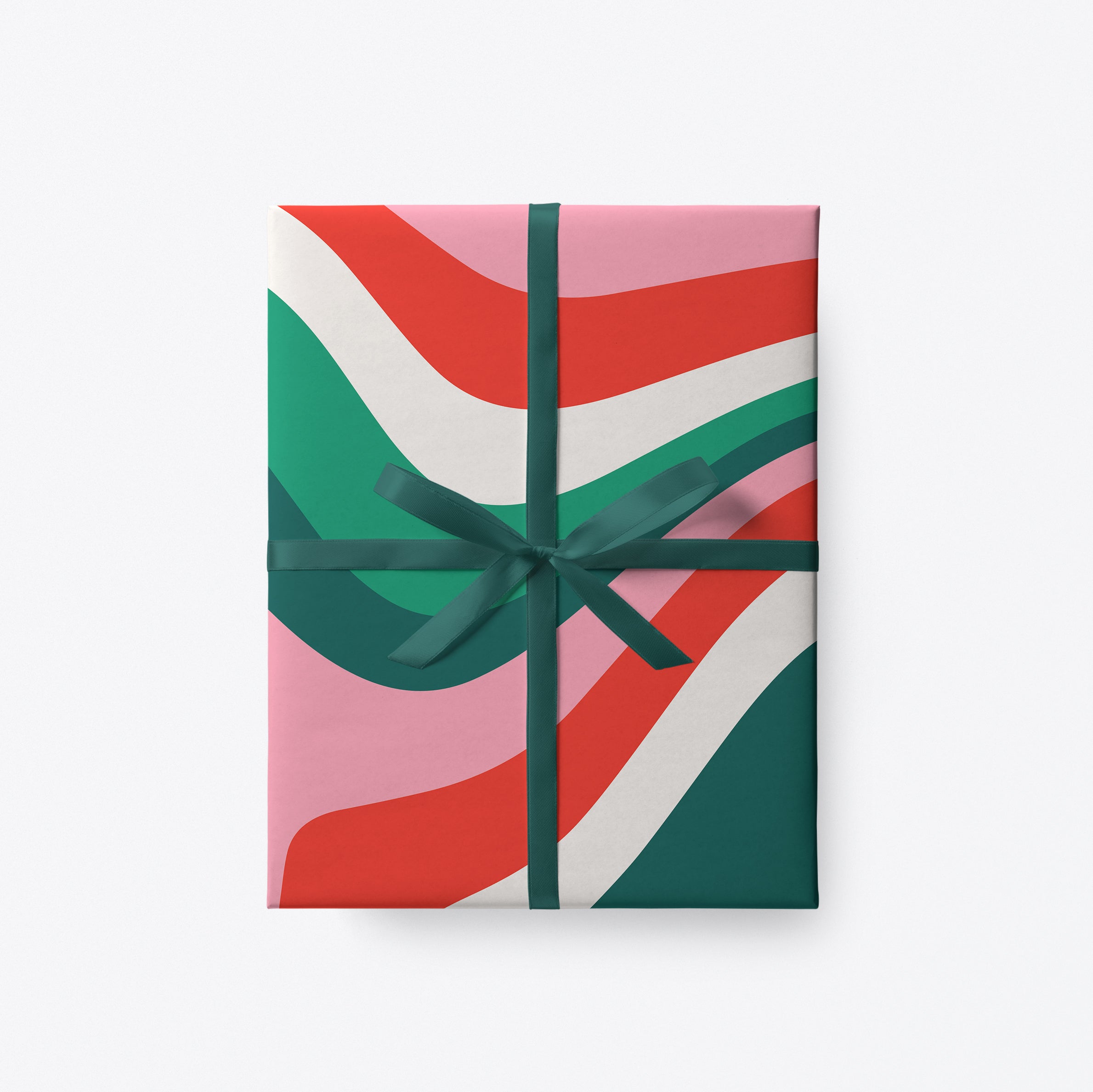 Festive wrapping paper with bold red, green and pink wavy design and dark green ribbon.