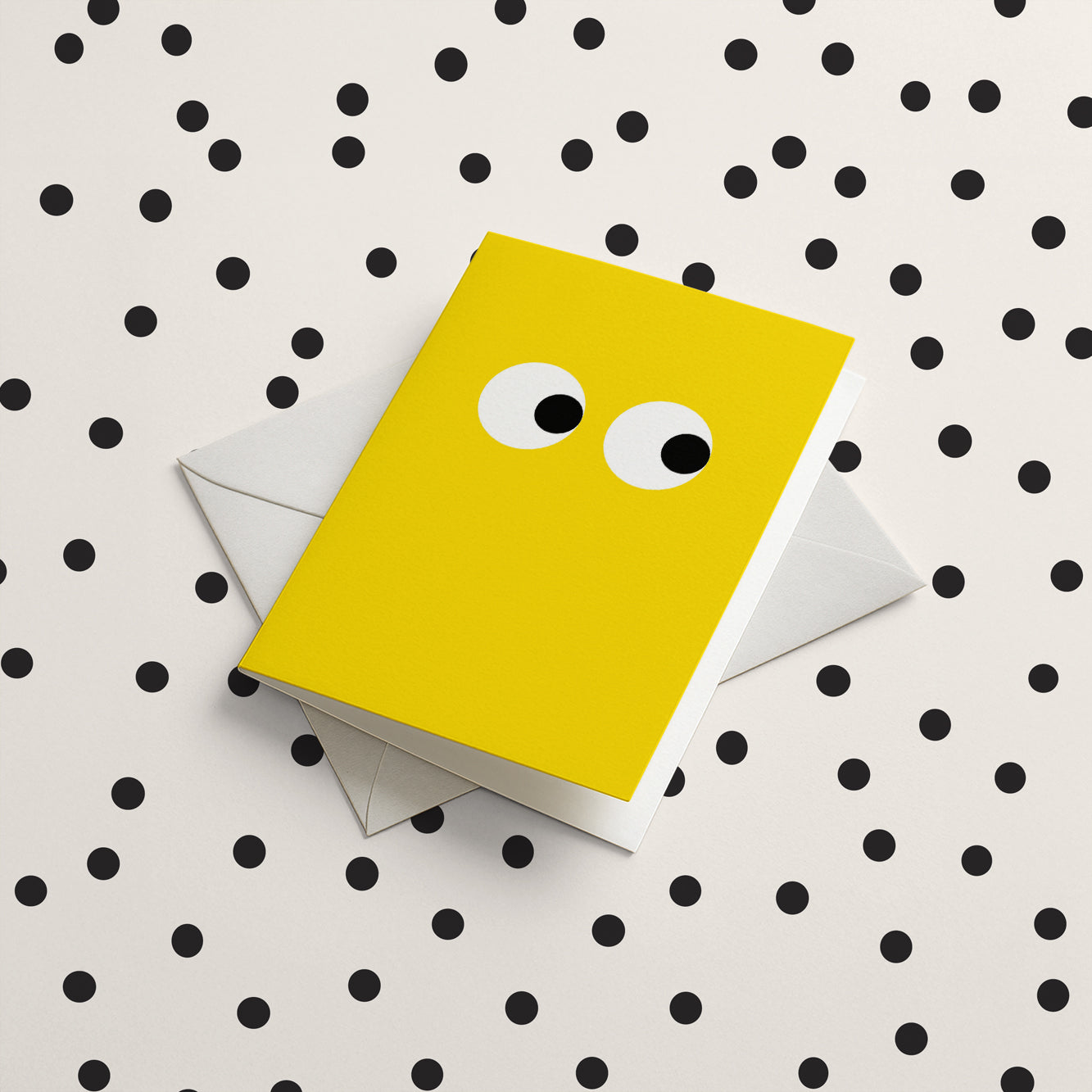 Yellow card with googly eyes on a polka dot background