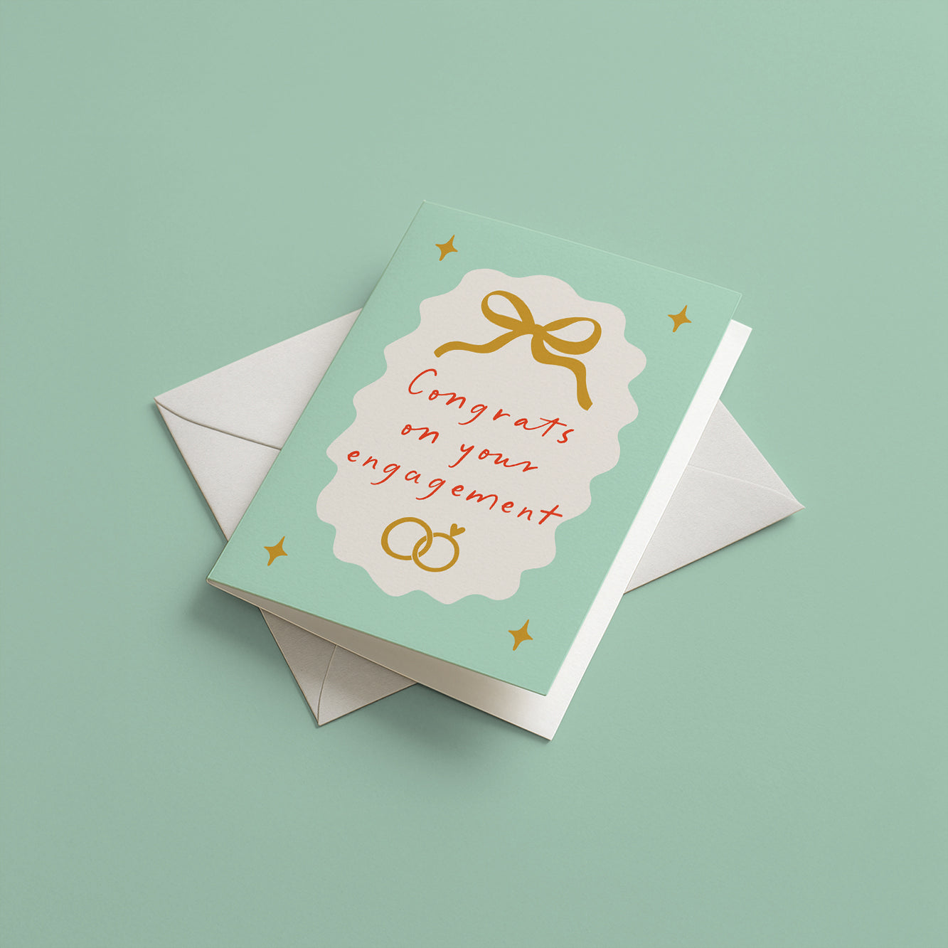 Engagement card with gold bow and rings on a light green background