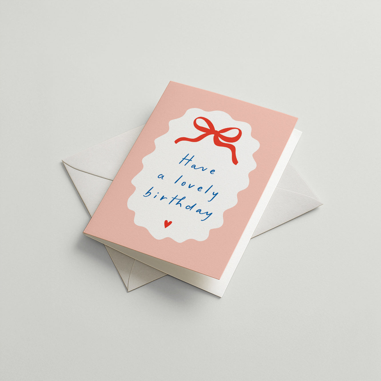 Pink birthday card with a red bow and text 'Have a lovely birthday' on a gray background