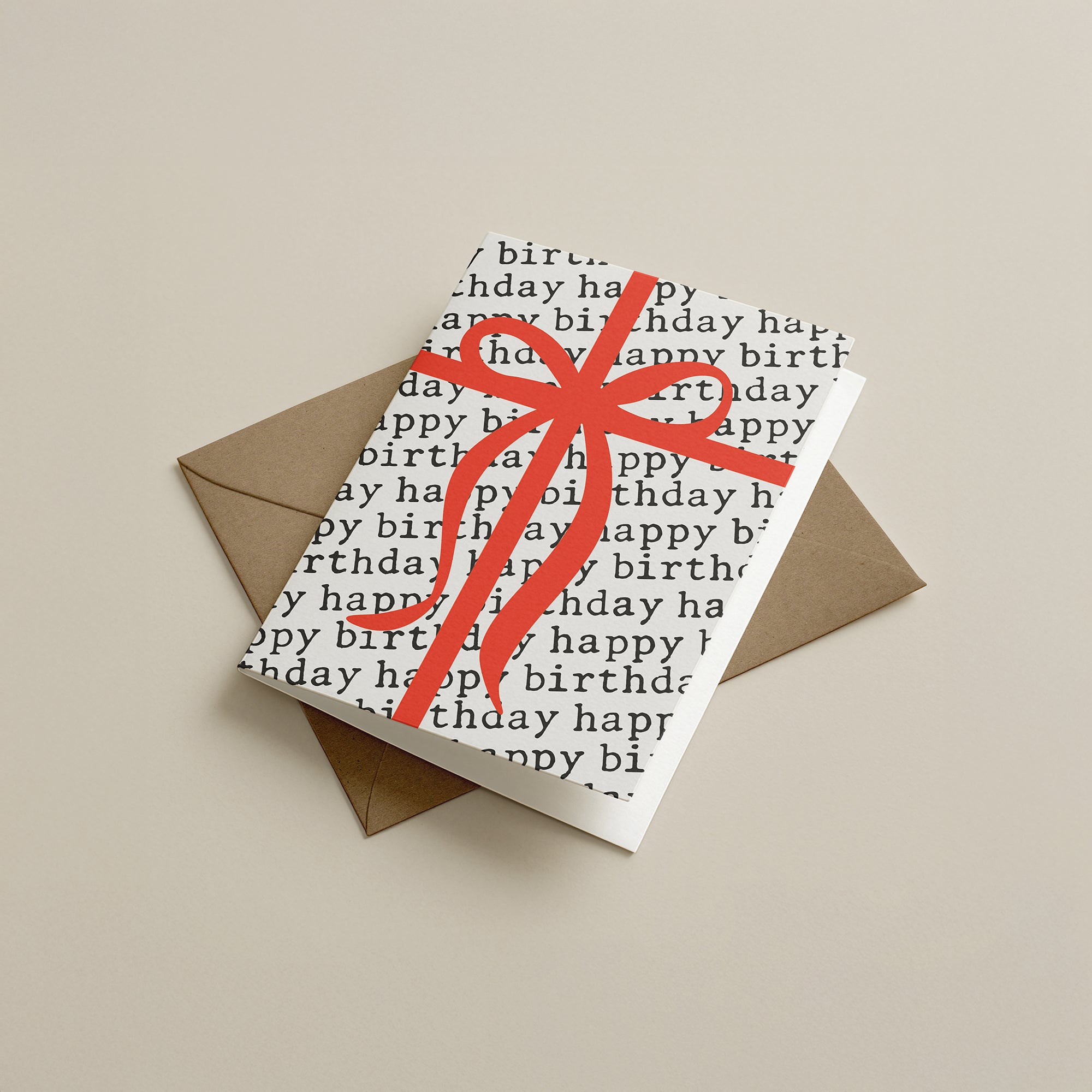Birthday card with red ribbon and kraft envelope on beige background