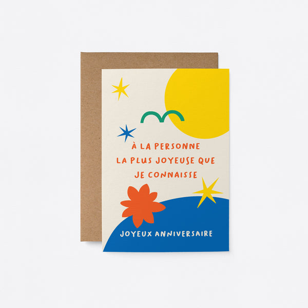 French birthday card with yellow sun green bird yellow stars blue figures and a text that says À la personne la plus joyeuse que je connaisse, joyeux anniversaire