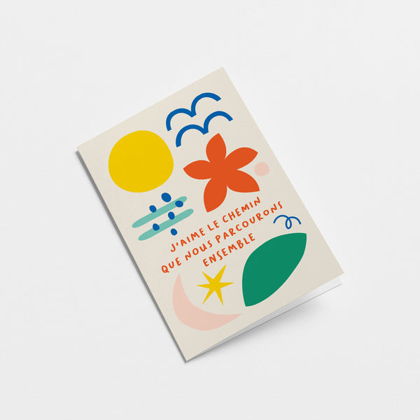 French Love card with yellow sun, blue birds, red flower, green, pink, blue and yellow figures and a text that says J’aime le chemin que nous parcourons ensemble  Edit alt text