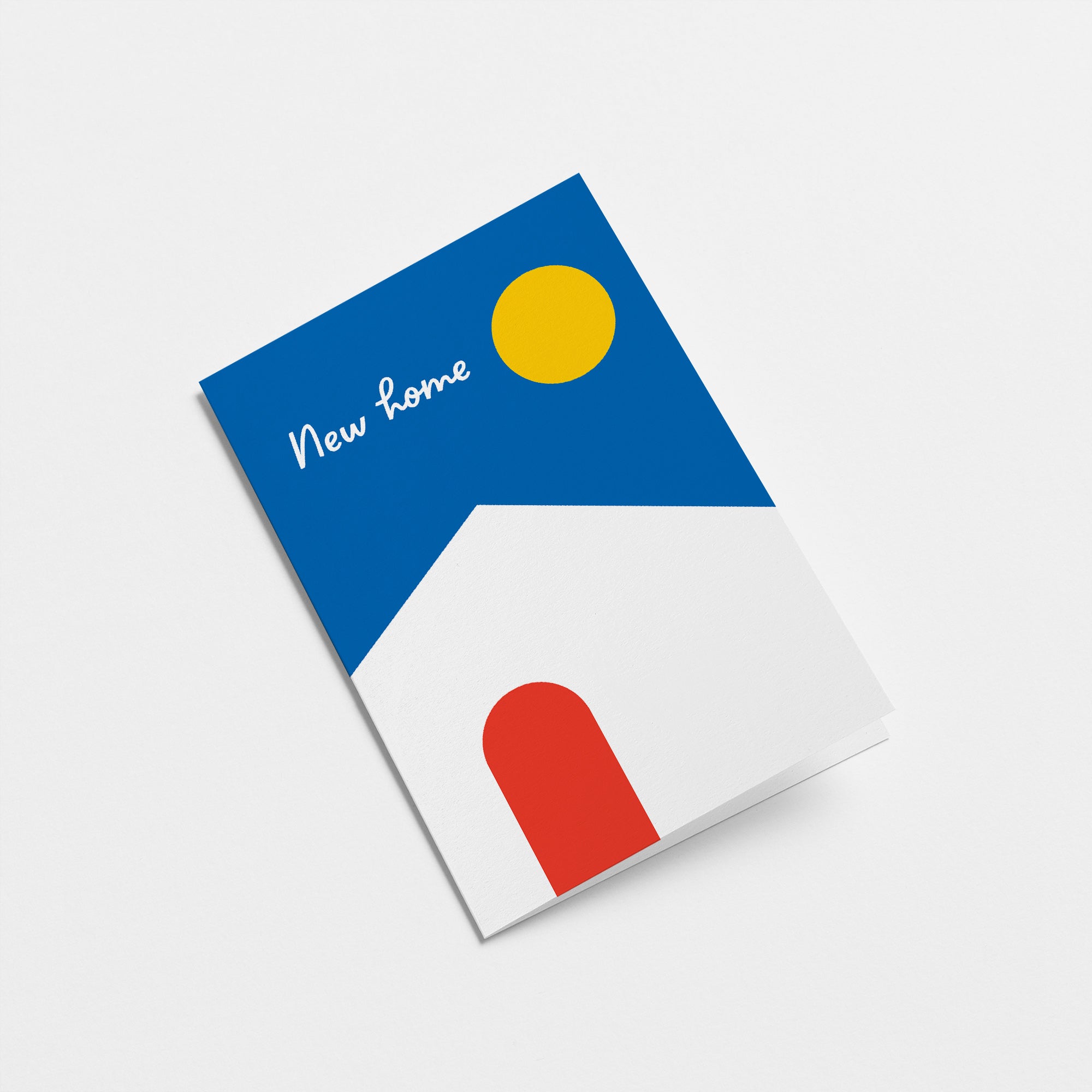 housewarming card with a white house, red door, blue sky and yellow sun and a text that says new home  Edit alt text