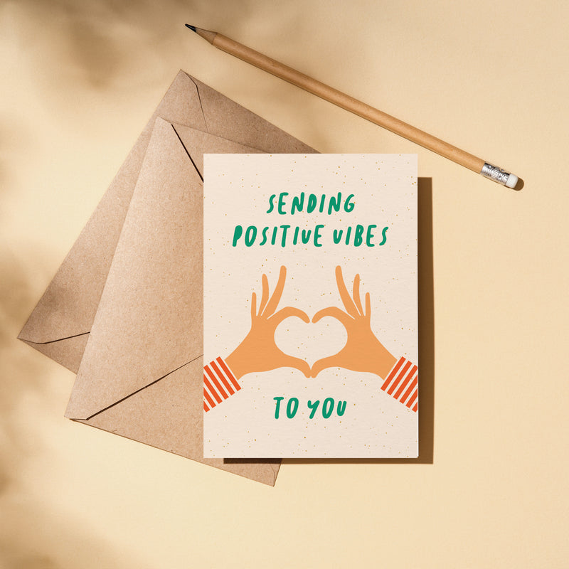 greeting card with two hands creating heart shape with fingers and a text that says sending positive vibes to you  Edit alt text