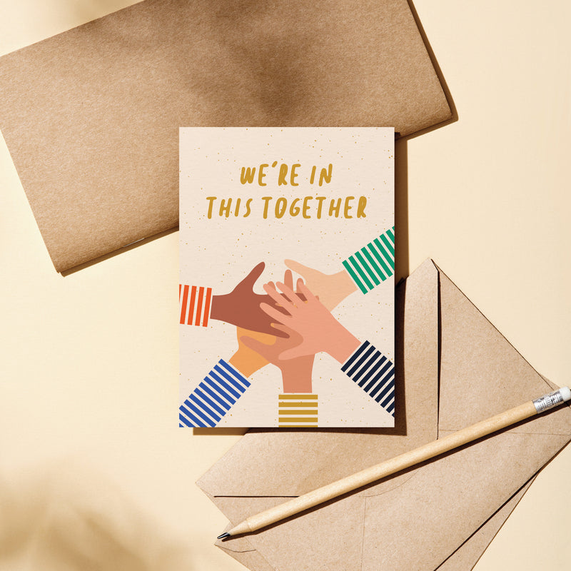 Friendship card with five different colored hands put on top of each other and a text that says we’re in this together  Edit alt text