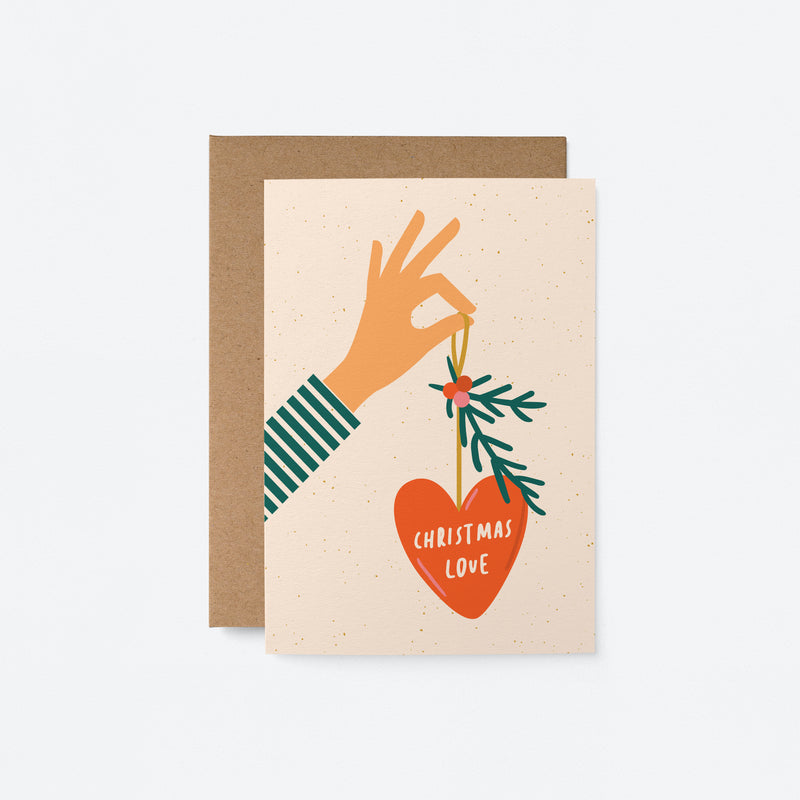 christmas card with a hand holding red christmas tree ornament and a text in it that says christmas love