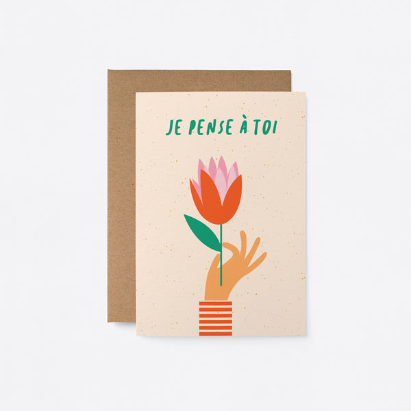 french Thinking of you card with a hand holding red tulip and a text that says Je pense à toi