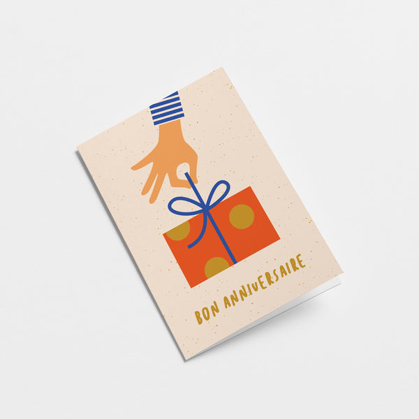 french birthday card with a hand holding a blue ribbon of a red birthday present and a text that says Bon anniversaire  Edit alt text